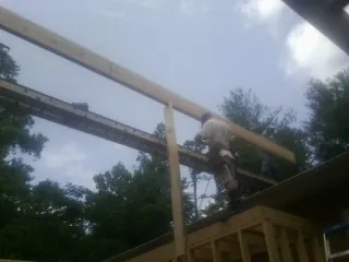 Carpenter setting a ridge beam over a new addition frame — Ice Dam Removal by Roofing Brothers in Burr