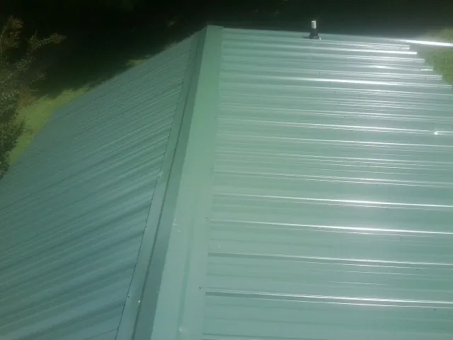 New green metal panels meeting at the ridge of a roof — Flat Roof Repair work by our crew in Burr