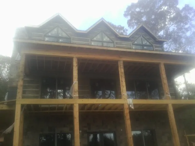 Dormers and porch framing on a large log home under construction — Roof Coating work by our crew in Burr
