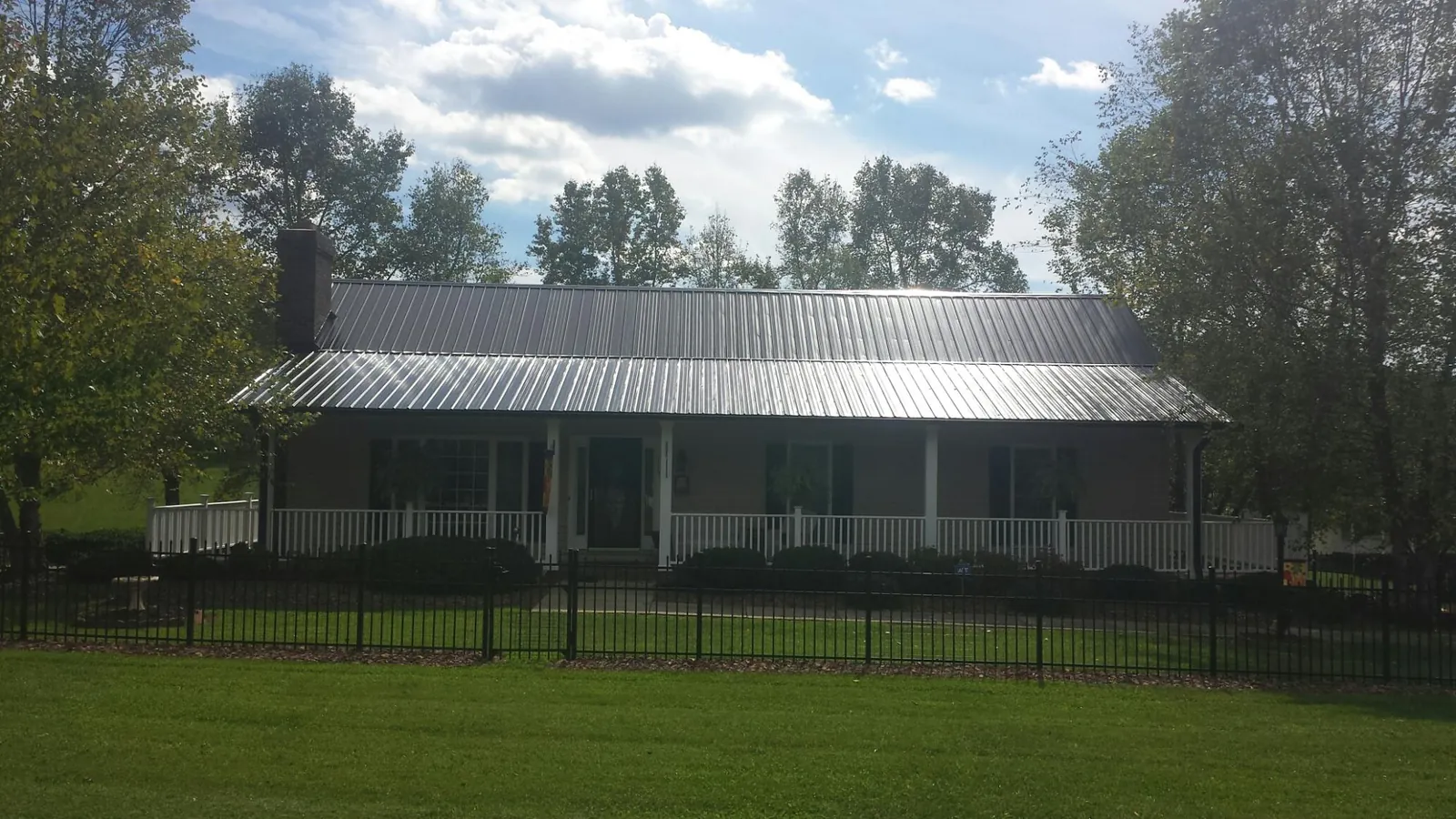 Gray metal roof on a brick ranch with a full width front porch — Gutter Guard Installation work by our crew in Burr