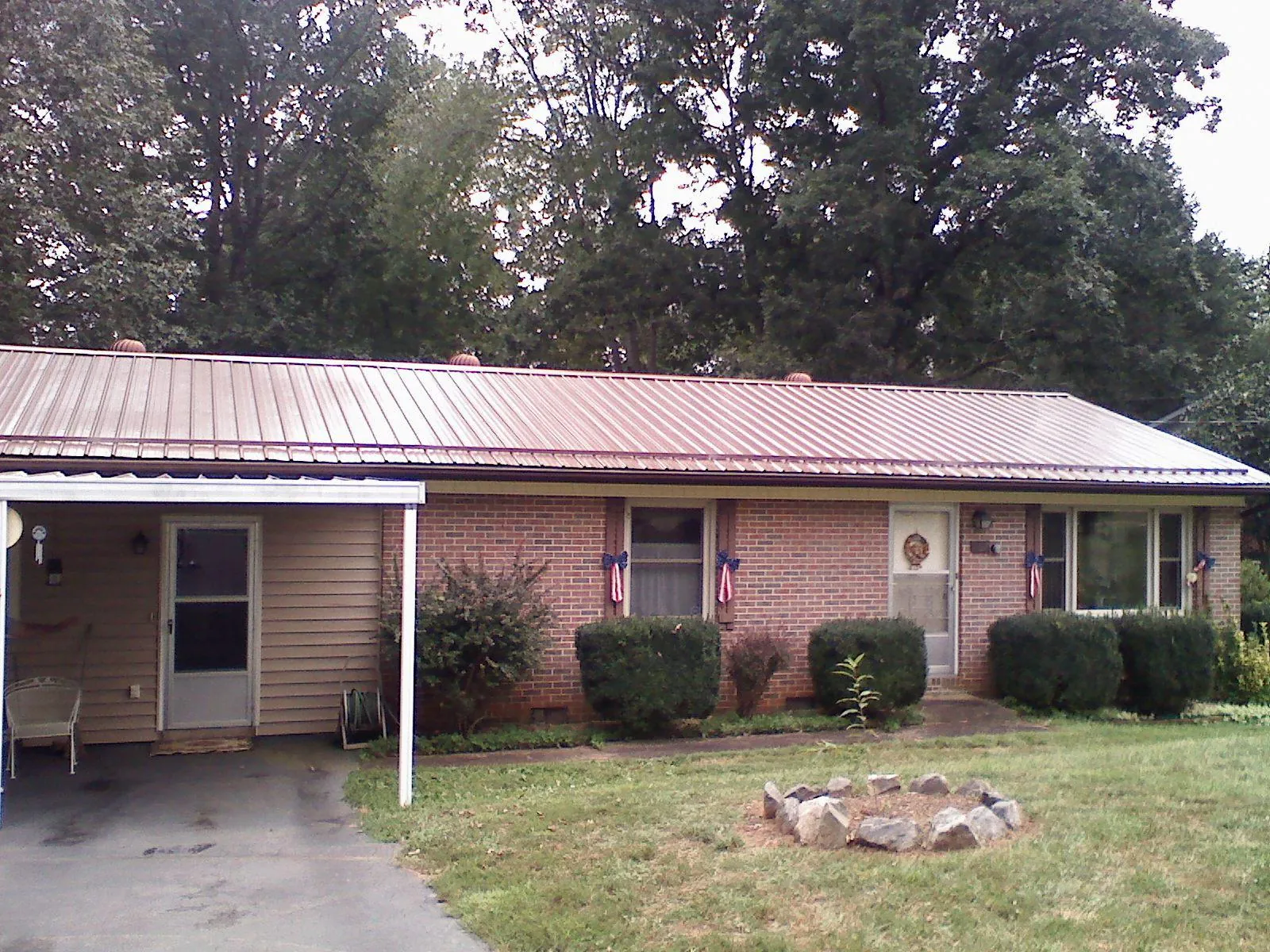 Bronze metal roof and carport on a brick ranch home — Roof Repair work by our crew in Burr