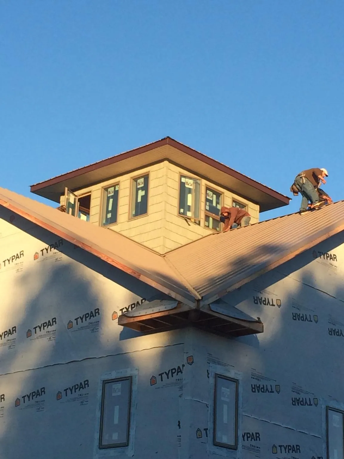 Roofers working around a rooftop cupola on a new metal roof at sunset — Roof Waterproofing in Burr by Roofing Brothers